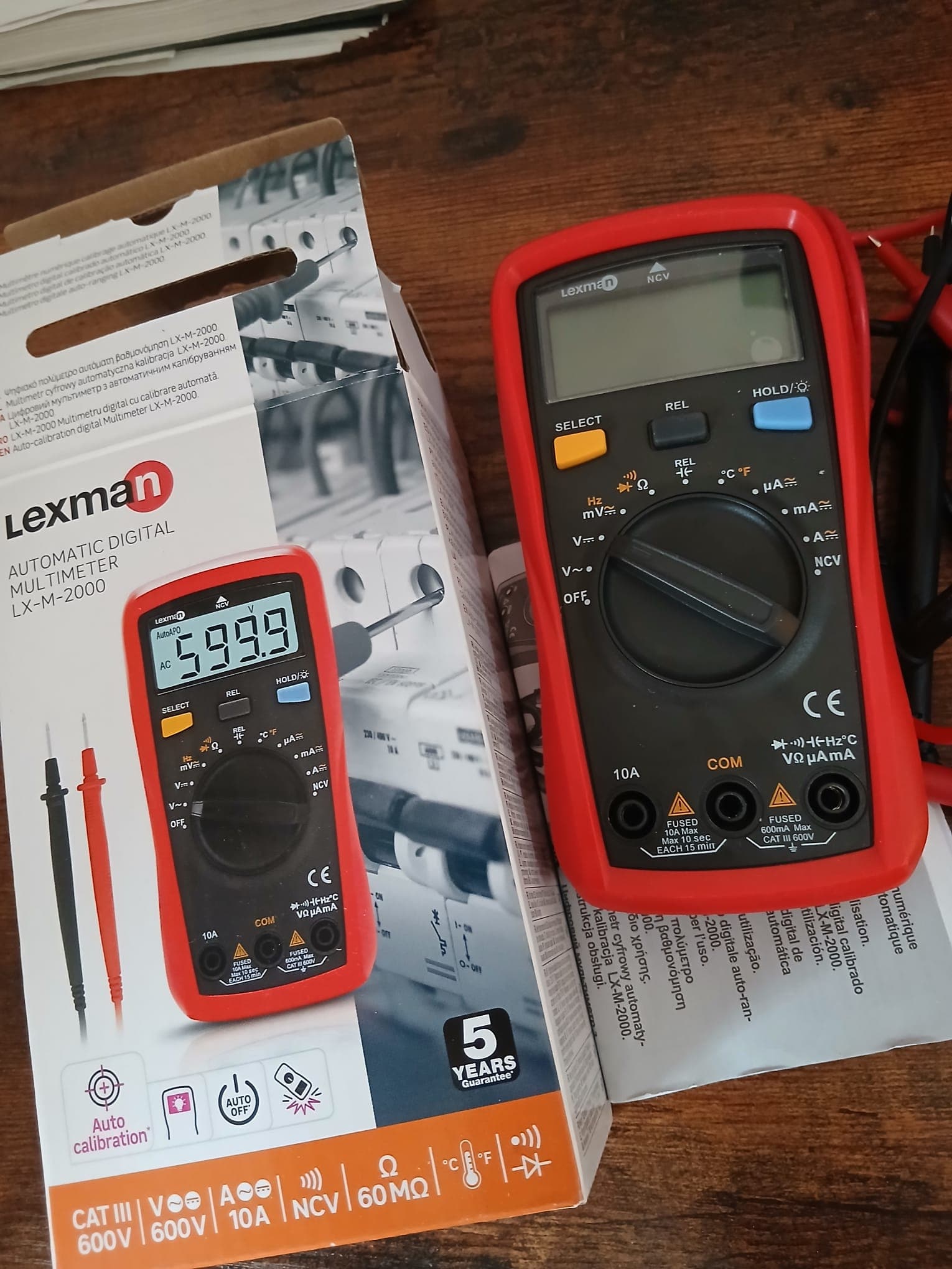 Lexman digital multimeter next to its box and the red and black probes.
