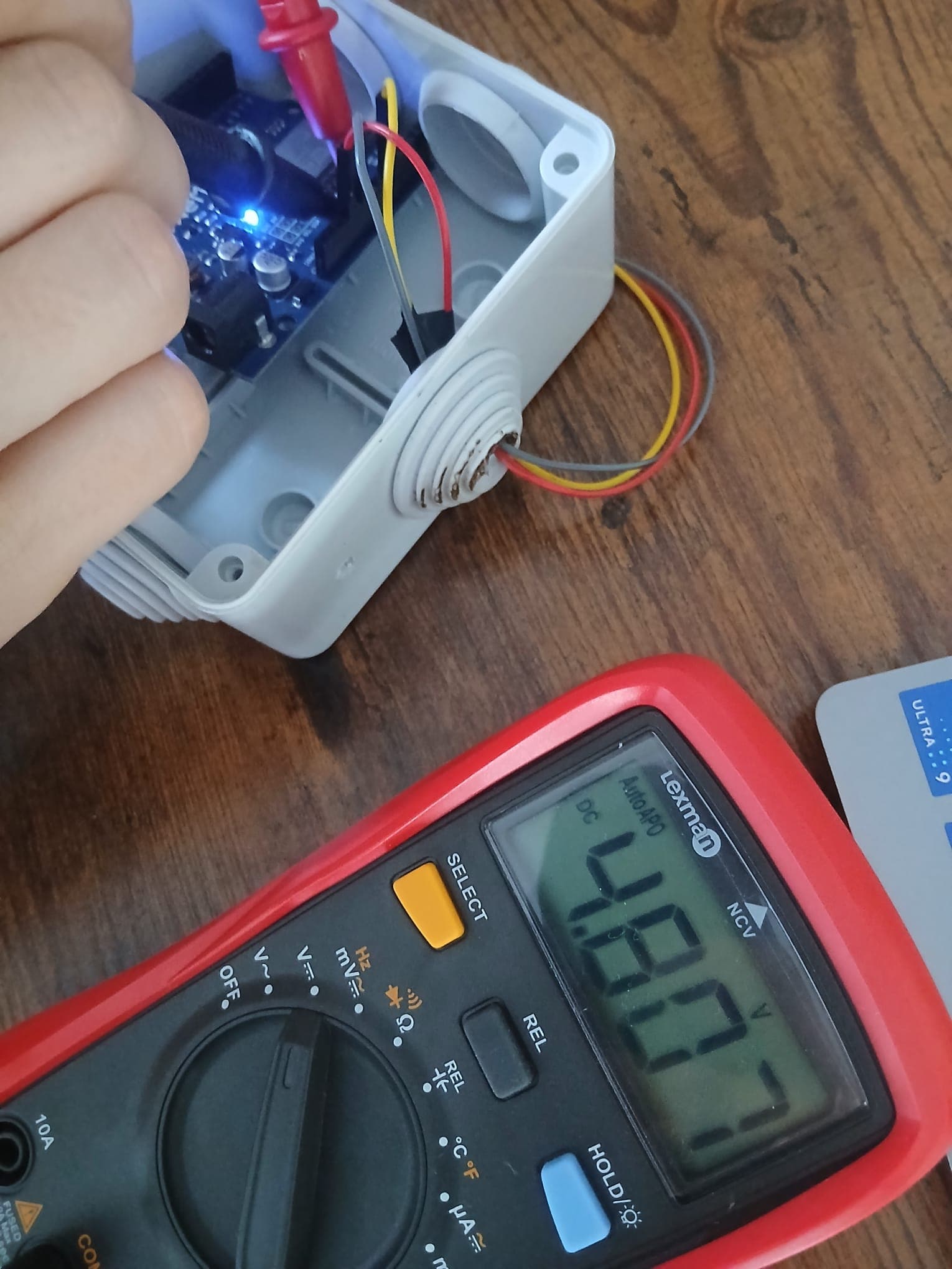 Multimeter probes on the VIN and GND pins of the Wemos powered by the power bank, with the voltage reading on the display.