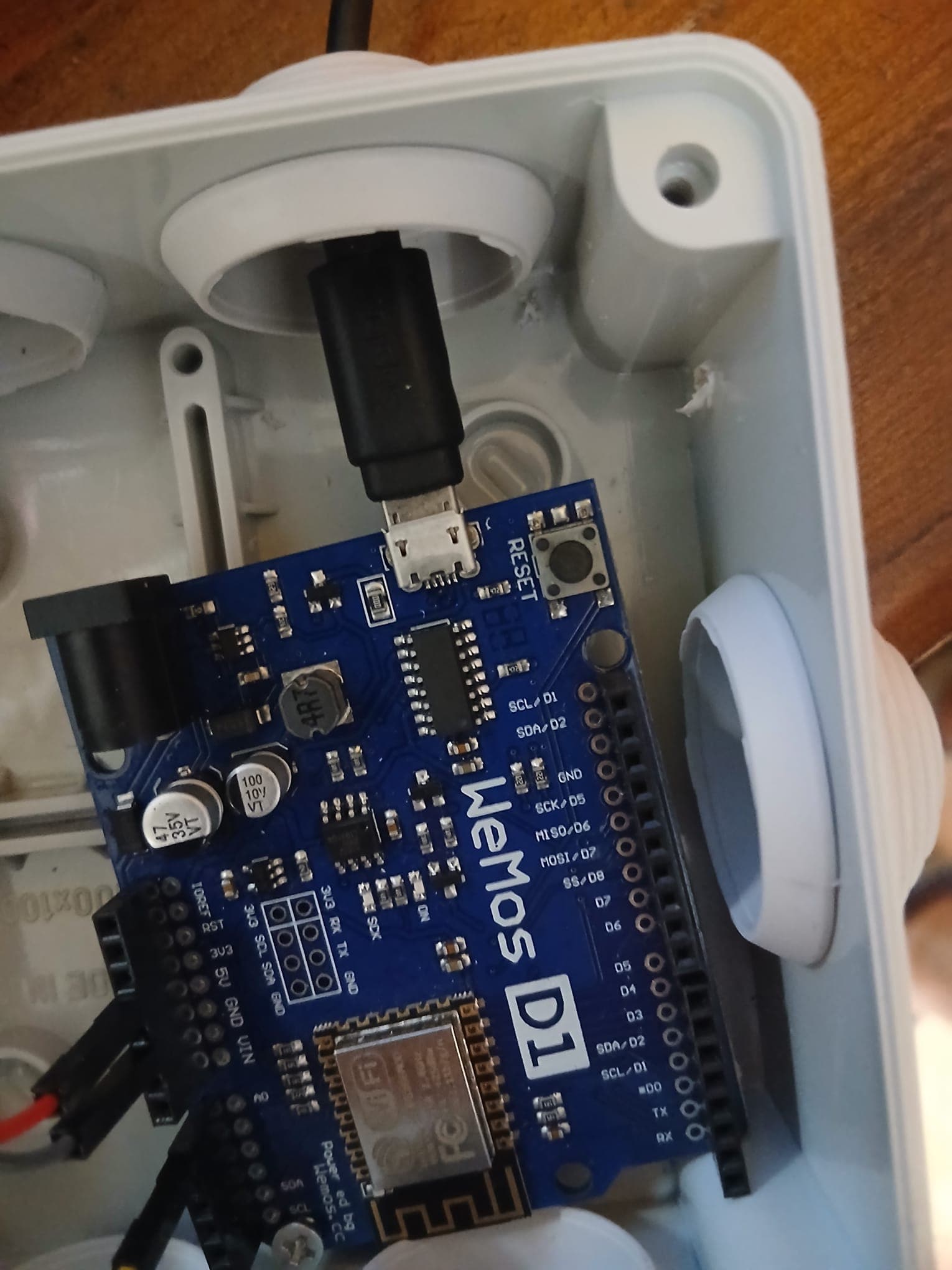 The Wemos board sitting inside a white weatherproof plastic enclosure, with the USB cable entering through a rubber gland.