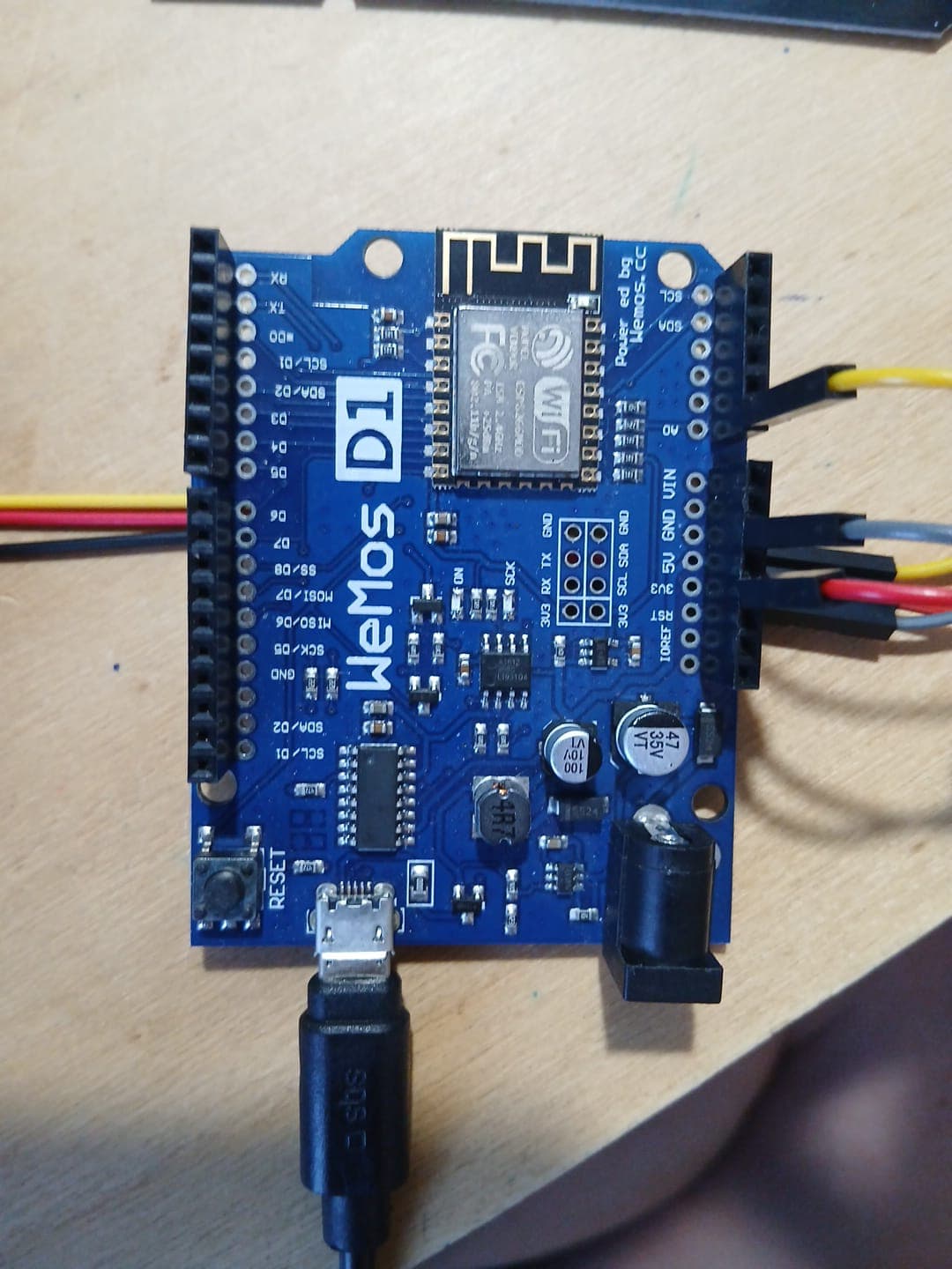 Top-down view of the blue Wemos board showing the ESP8266 Wi-Fi module and the labelled header pins.
