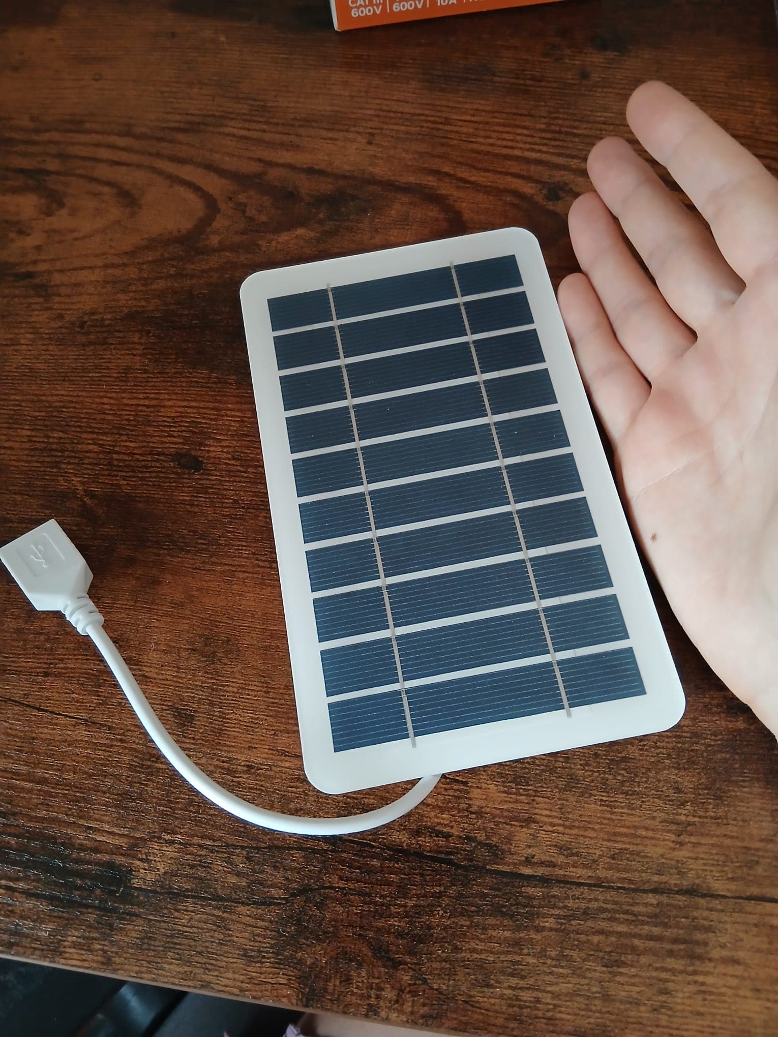 Small rectangular solar panel with a USB cable lying on a table.